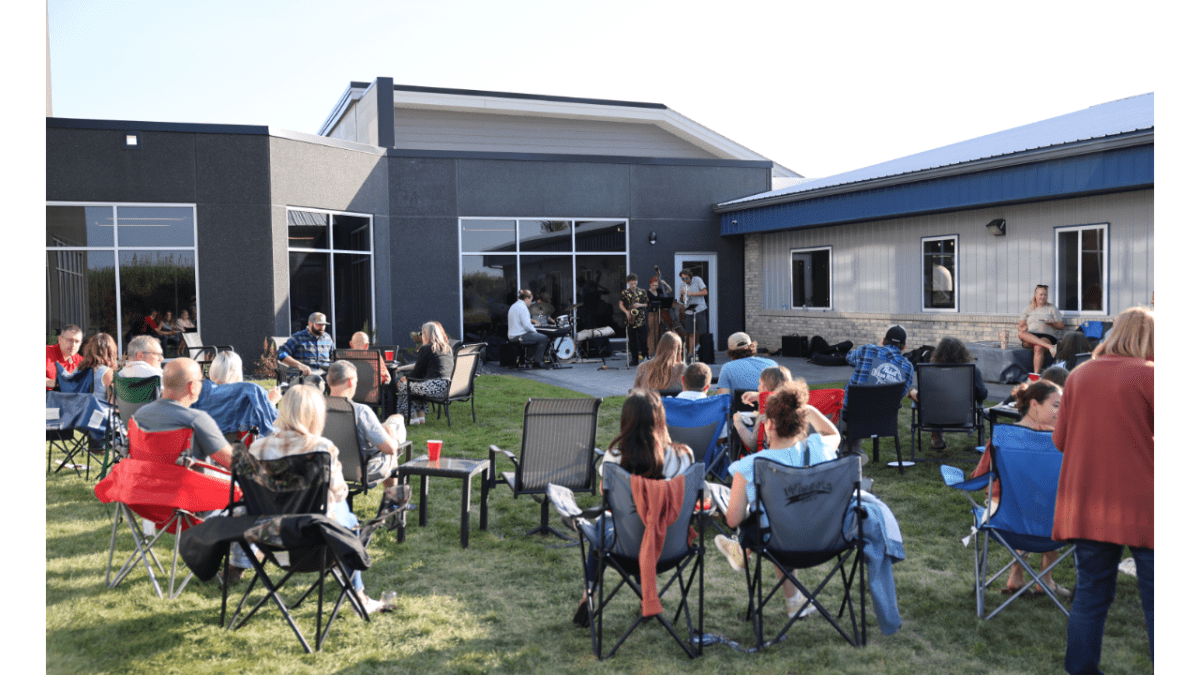 Picture of the Elite EXTRA team in their headquarters' courtyard sitting and listening to live music during the company event